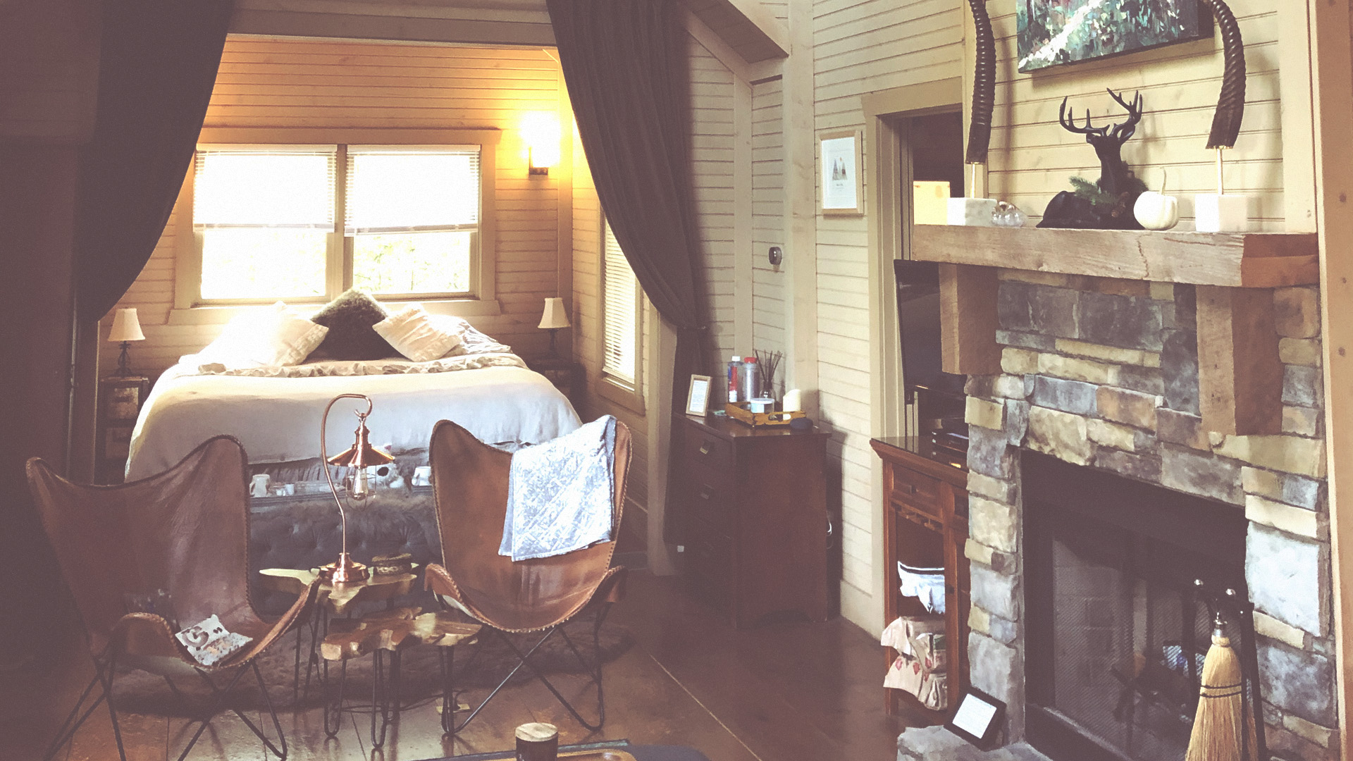 A cozy sleeping area and seating beside the cabin’s stone fireplace